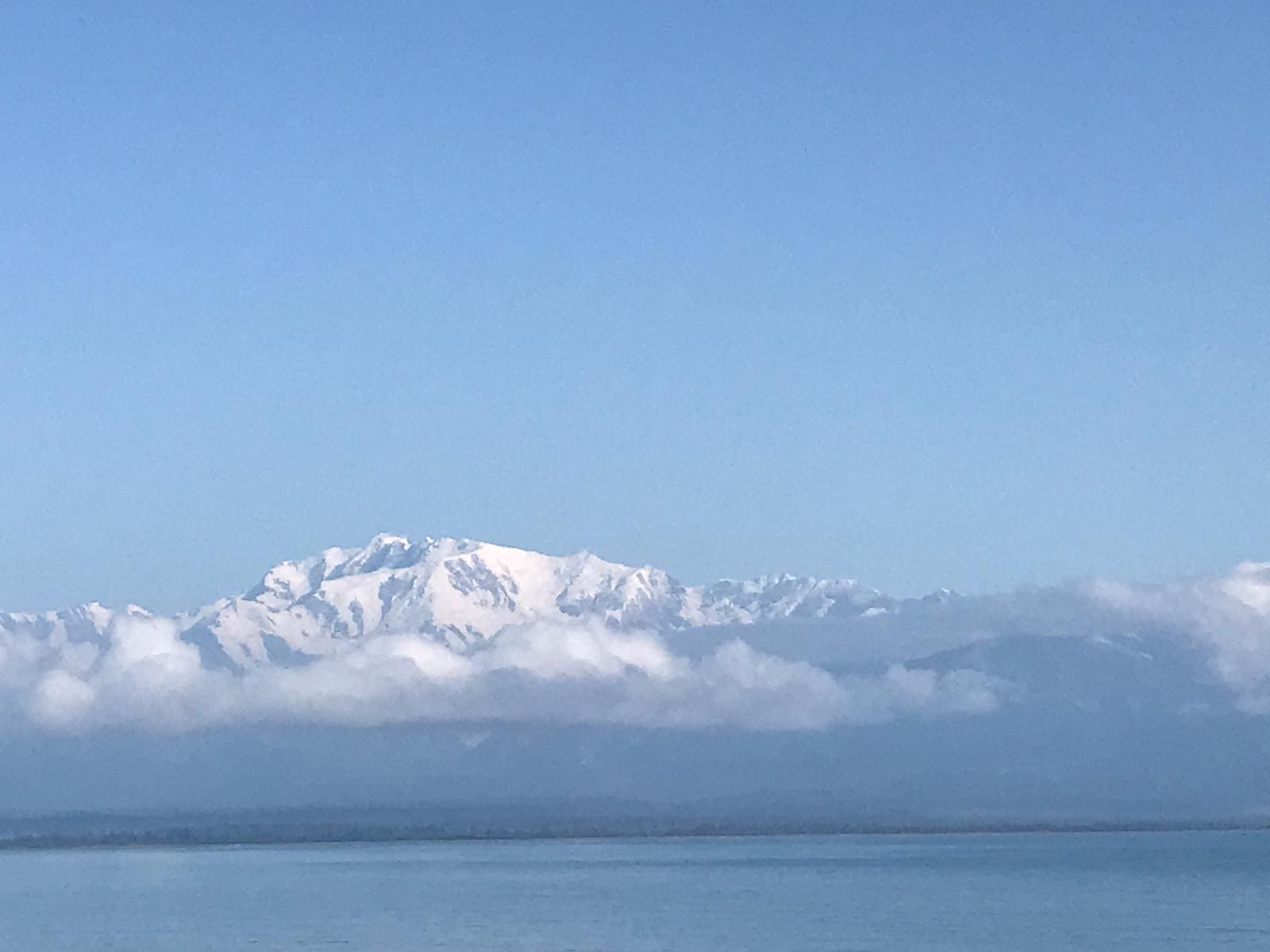 A large cloud is in the sky over the ocean.