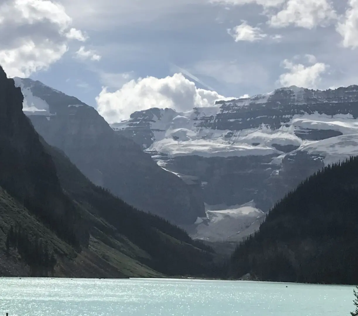 A lake with mountains in the background and clouds