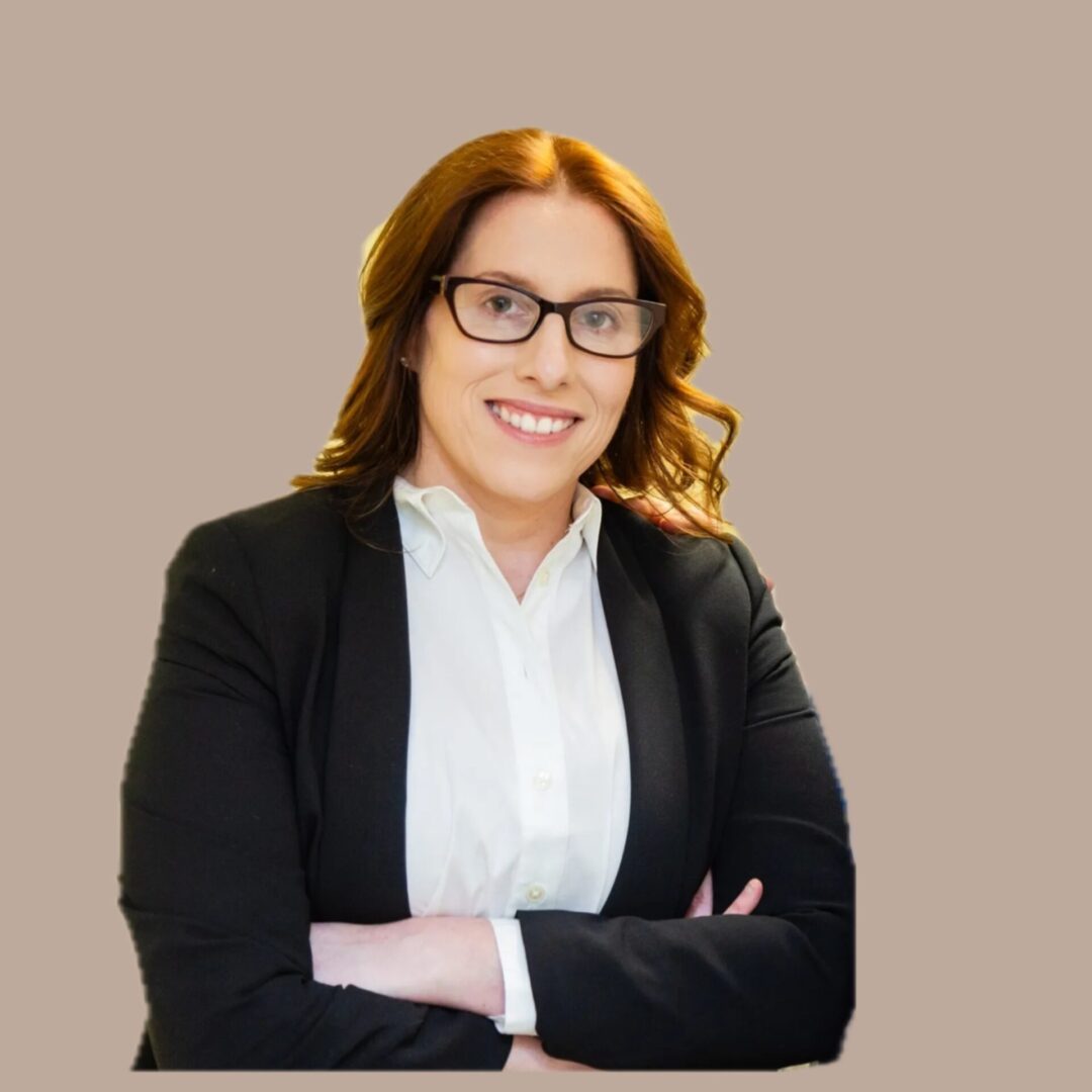 A woman with glasses and red hair wearing a black jacket.